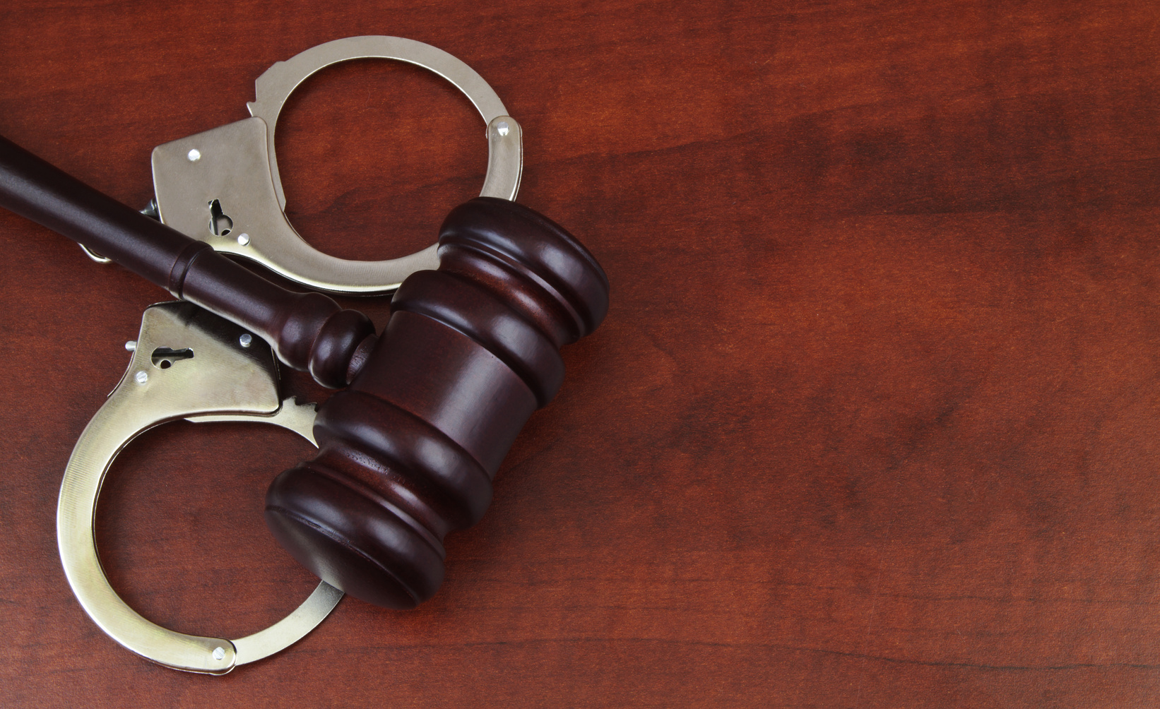 Wooden gavel on handcuffs close up.